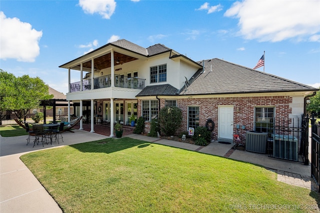 rear view of property featuring a yard, central AC unit, a patio, and a balcony