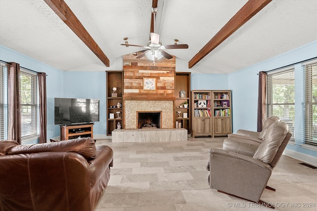 living room featuring a wealth of natural light, a large fireplace, ceiling fan, and lofted ceiling with beams