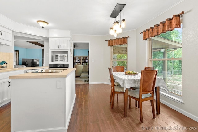 interior space featuring hardwood / wood-style flooring, white microwave, decorative light fixtures, and white cabinets