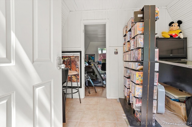 interior space with light tile patterned floors and wooden walls