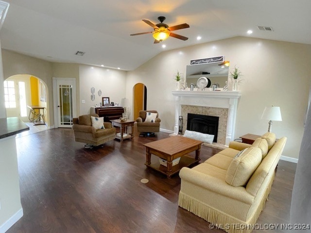 living room with vaulted ceiling, dark wood-type flooring, ceiling fan, and a tile fireplace