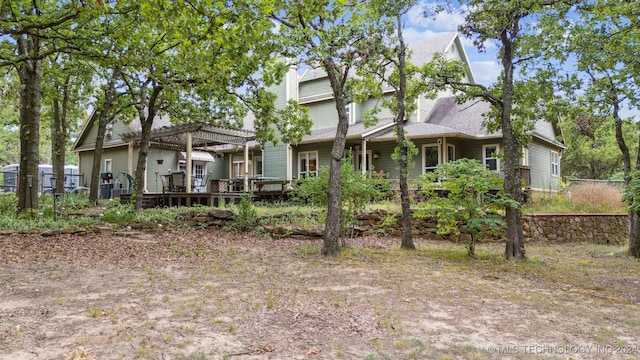 rear view of property featuring a pergola and a deck