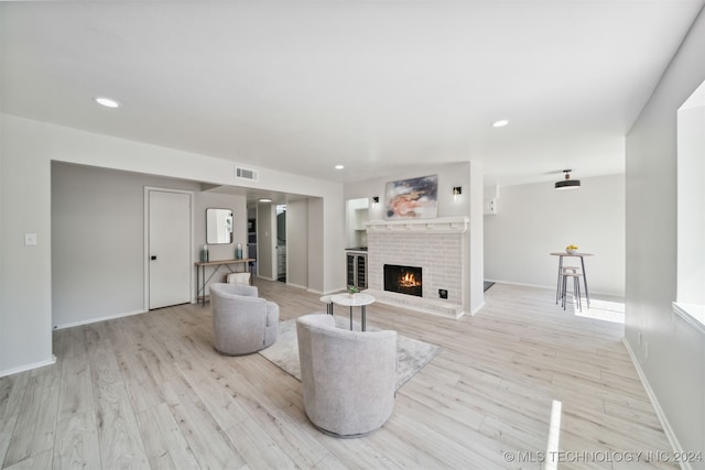 living room with light wood-type flooring and a brick fireplace