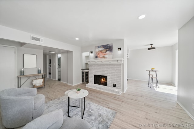 living room with a brick fireplace and light hardwood / wood-style floors