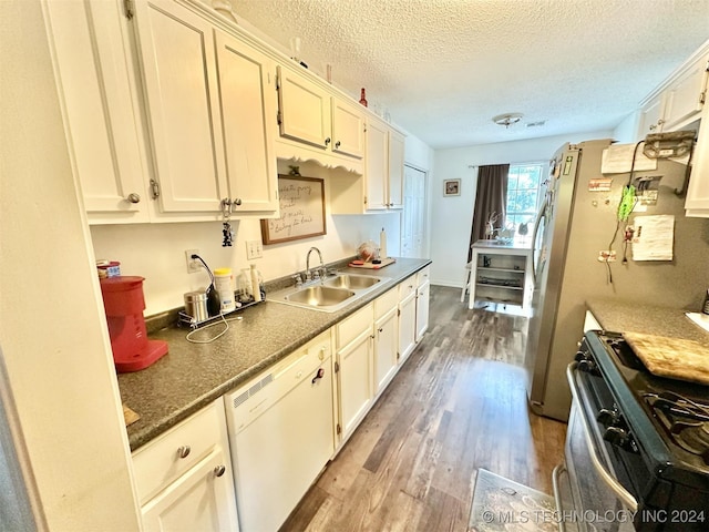 kitchen with stainless steel range with gas stovetop, a textured ceiling, dishwasher, sink, and hardwood / wood-style flooring