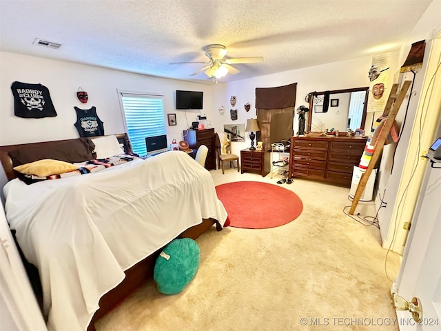 bedroom featuring light carpet, a textured ceiling, and ceiling fan