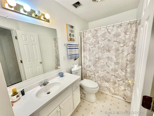 bathroom featuring a textured ceiling, vanity, toilet, and curtained shower