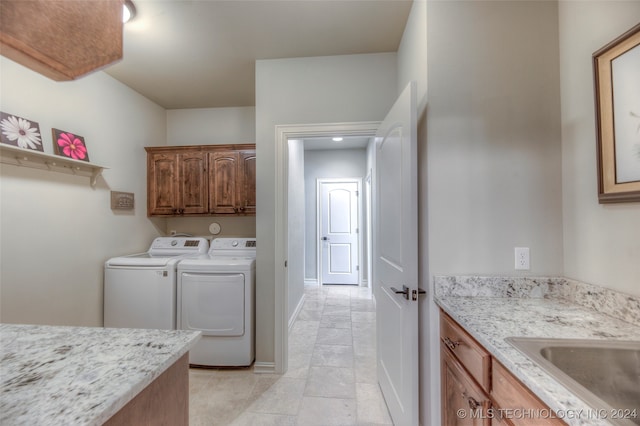 washroom with separate washer and dryer, sink, light tile patterned floors, and cabinets