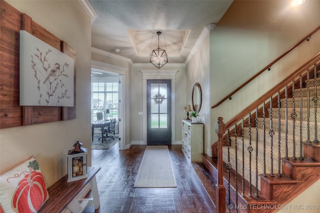 entrance foyer featuring ornamental molding, dark wood-type flooring, and a notable chandelier