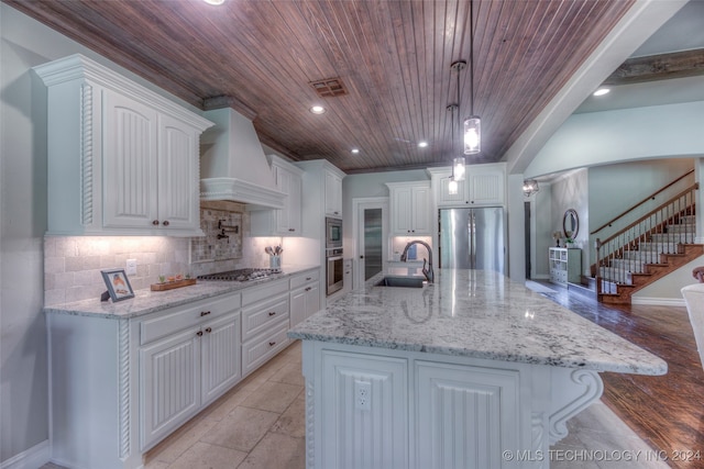 kitchen featuring white cabinetry, a spacious island, decorative light fixtures, appliances with stainless steel finishes, and custom exhaust hood