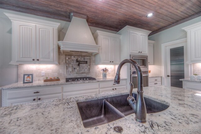 kitchen featuring white cabinetry, sink, appliances with stainless steel finishes, and custom exhaust hood