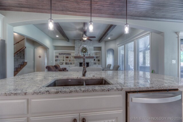 kitchen with stainless steel dishwasher, ceiling fan, beam ceiling, decorative light fixtures, and white cabinets