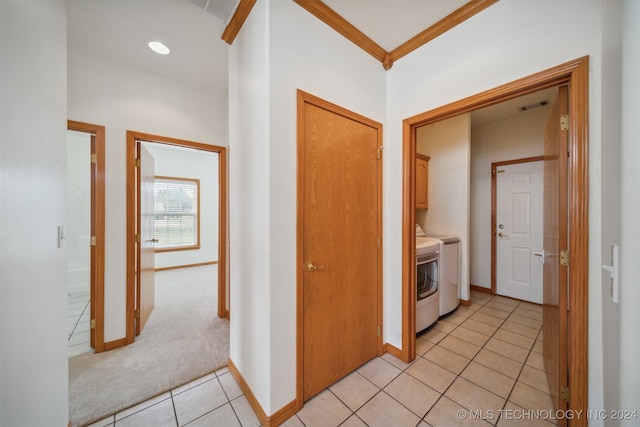 corridor with light carpet, crown molding, and washing machine and dryer