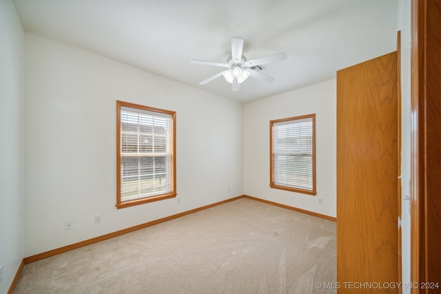 spare room with ceiling fan and light colored carpet