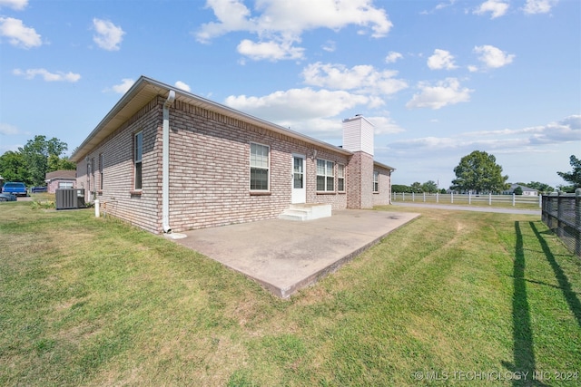 rear view of property featuring a lawn, a patio area, and central air condition unit