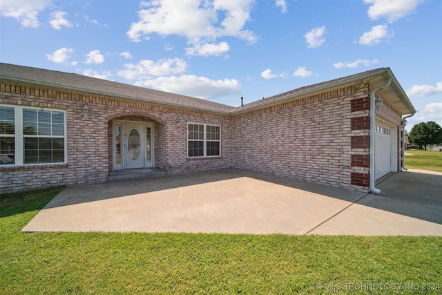 back of property featuring a lawn and a garage