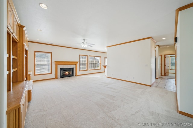 unfurnished living room with ceiling fan, a fireplace, light carpet, and crown molding