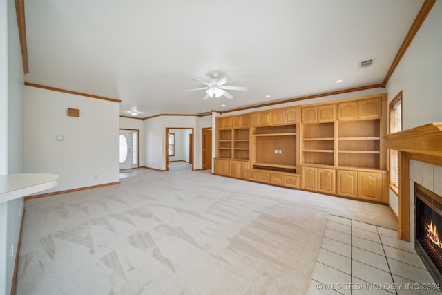 unfurnished living room with ceiling fan, light colored carpet, crown molding, and a tile fireplace