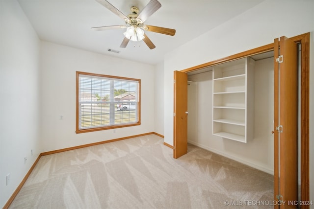 unfurnished bedroom with ceiling fan, a closet, and light carpet