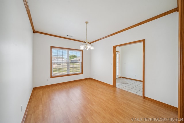 spare room with light wood-type flooring, ornamental molding, and a chandelier