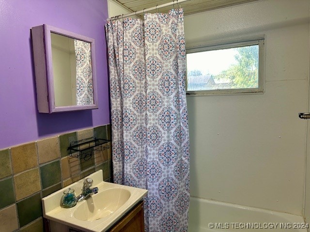 bathroom with vanity, shower / bath combination with curtain, and tasteful backsplash