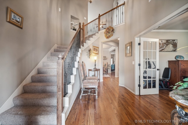 foyer featuring crown molding, hardwood / wood-style floors, and a high ceiling