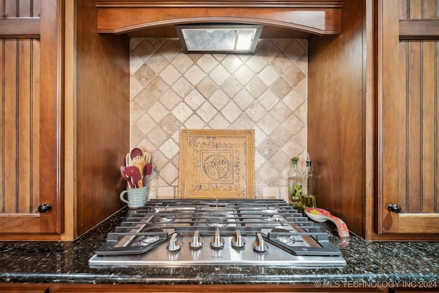 room details with stainless steel gas stovetop, dark stone countertops, and decorative backsplash