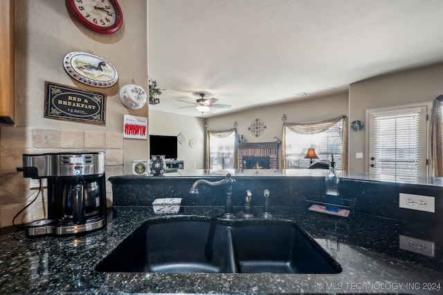 kitchen featuring dark stone counters, sink, and ceiling fan