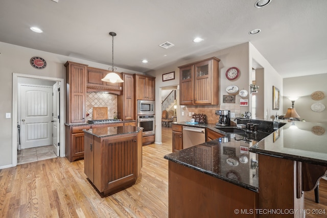 kitchen featuring pendant lighting, light wood-type flooring, kitchen peninsula, stainless steel appliances, and backsplash