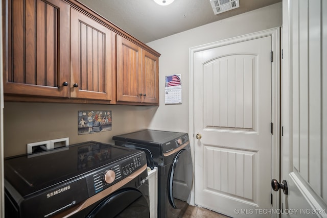 clothes washing area with cabinets and washer and dryer