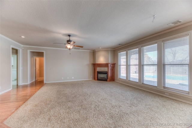 unfurnished living room with baseboards, visible vents, a fireplace, ornamental molding, and a textured ceiling