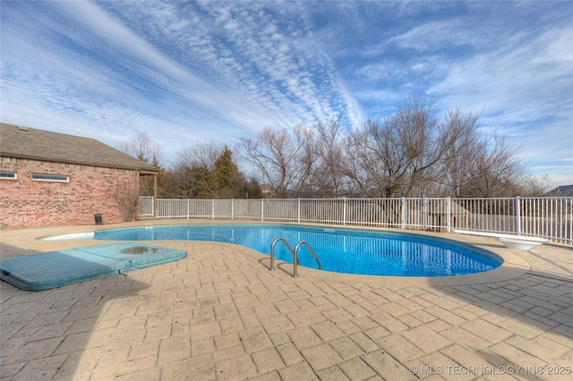 view of swimming pool with a patio area, a diving board, a fenced in pool, and fence