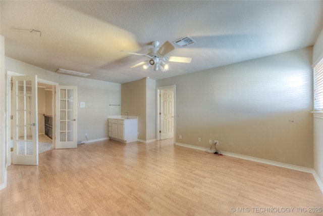 spare room with visible vents, ceiling fan, light wood-type flooring, french doors, and a sink