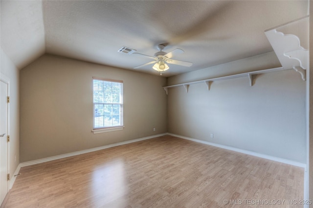 additional living space with light wood-type flooring, visible vents, lofted ceiling, a ceiling fan, and baseboards