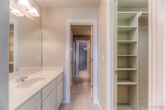 bathroom featuring tile patterned flooring, a spacious closet, and vanity