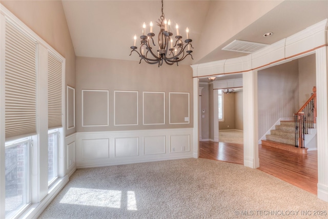 unfurnished dining area with visible vents, carpet floors, lofted ceiling, and a decorative wall