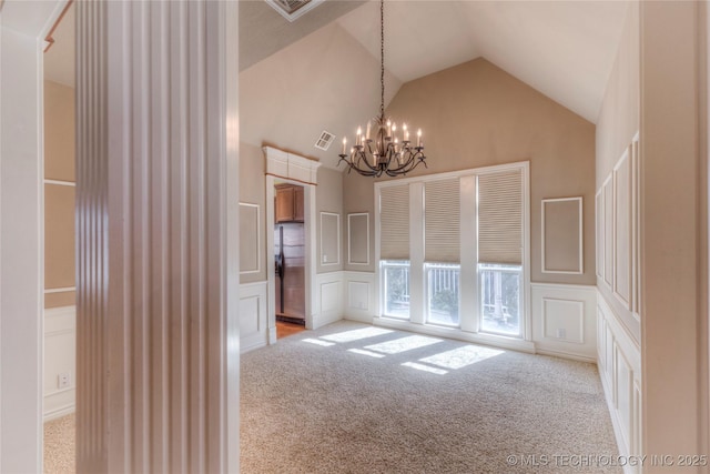 unfurnished dining area featuring visible vents, high vaulted ceiling, a decorative wall, a notable chandelier, and light colored carpet