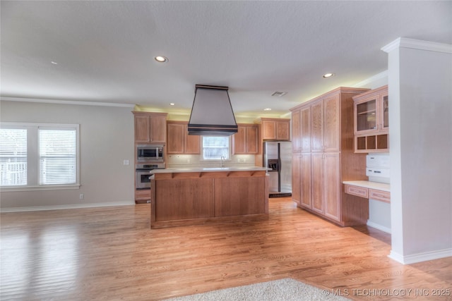 kitchen featuring a kitchen island, light wood-style flooring, a sink, light countertops, and appliances with stainless steel finishes