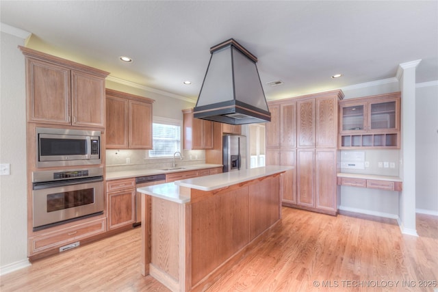 kitchen with light wood-type flooring, ornamental molding, a kitchen island, stainless steel appliances, and light countertops