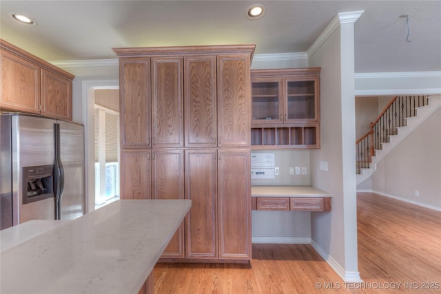 kitchen featuring ornamental molding, stainless steel fridge with ice dispenser, light wood-type flooring, and built in study area