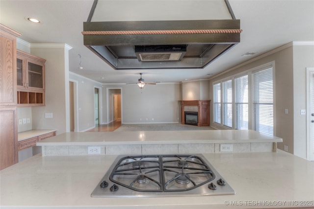 kitchen featuring ornamental molding, wall chimney exhaust hood, a fireplace, and stainless steel gas cooktop