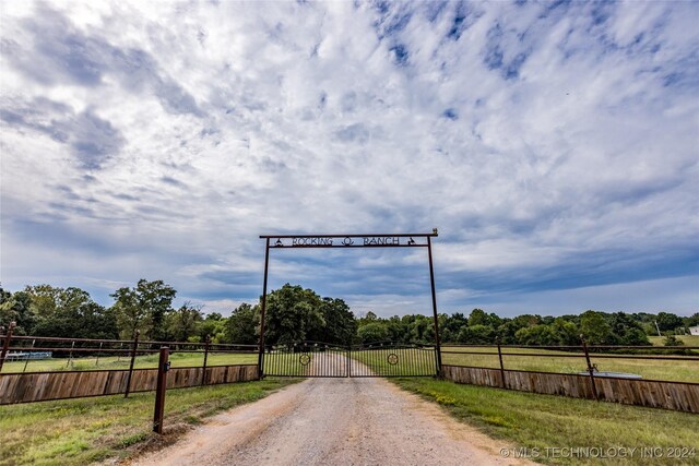 view of road with a gate, a gated entry, and a rural view