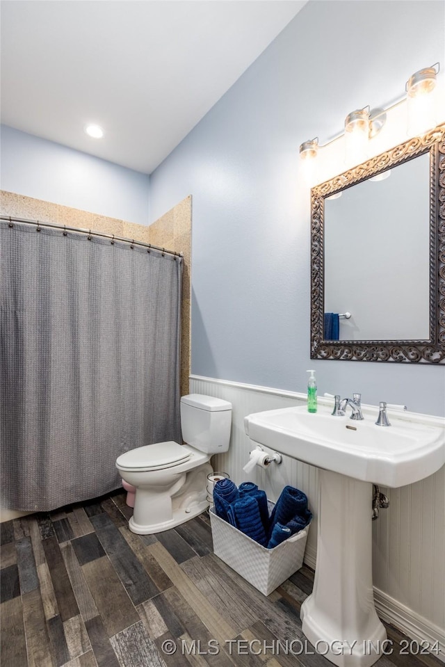 bathroom featuring a sink, toilet, a wainscoted wall, wood finished floors, and a shower with curtain