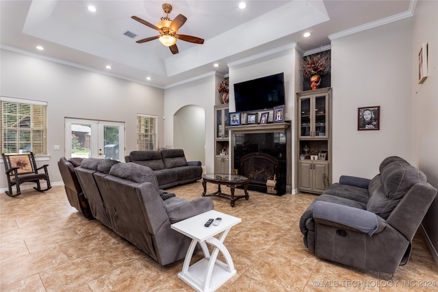 living room with a tray ceiling, french doors, a premium fireplace, and ceiling fan