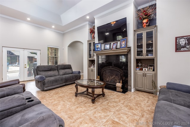 living room with ornamental molding, french doors, a towering ceiling, and built in shelves