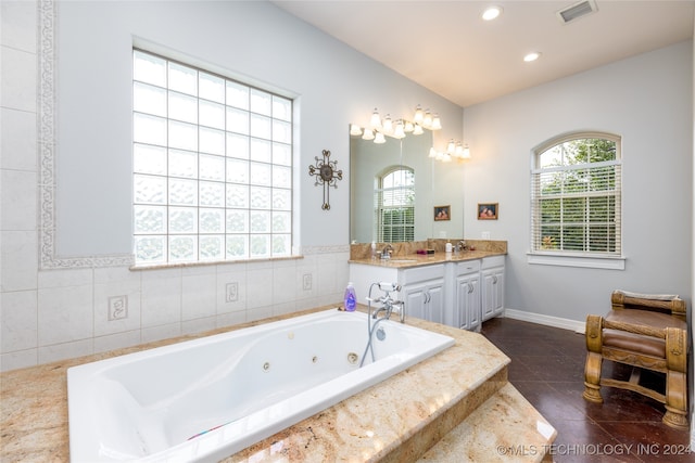 bathroom with tile patterned flooring, tiled tub, and vanity