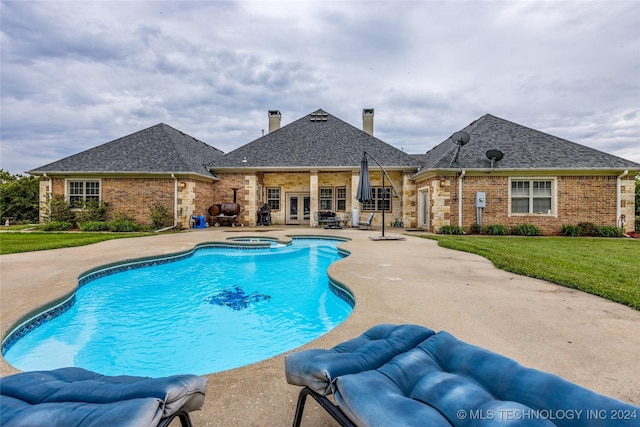 view of swimming pool featuring french doors, a patio, a lawn, and a pool with connected hot tub
