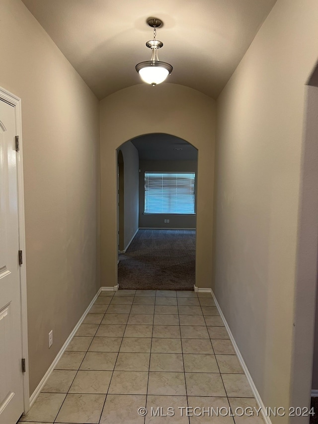 hall featuring vaulted ceiling and light tile patterned floors