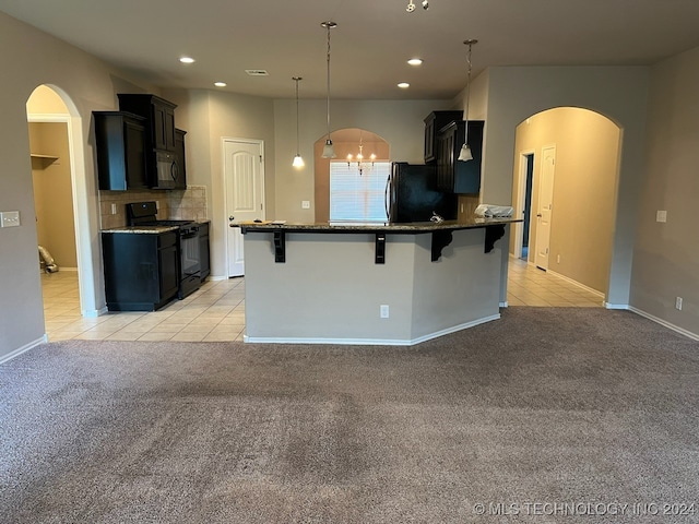 kitchen with an inviting chandelier, light colored carpet, black appliances, a kitchen breakfast bar, and pendant lighting