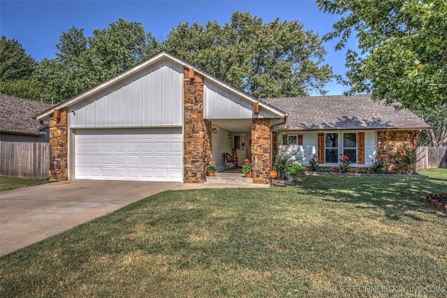 mid-century home featuring stone siding, a front yard, an attached garage, and fence